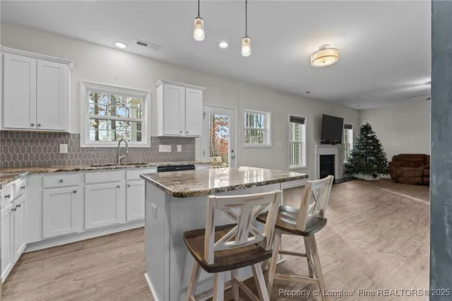 a kitchen with stainless steel appliances granite countertop a stove top oven a sink dishwasher and white cabinets with wooden floor