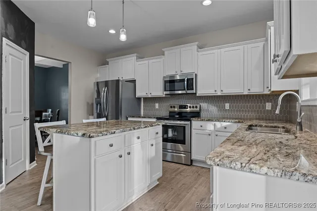 a kitchen with stainless steel appliances granite countertop a stove top oven a sink a refrigerator and a granite counter tops