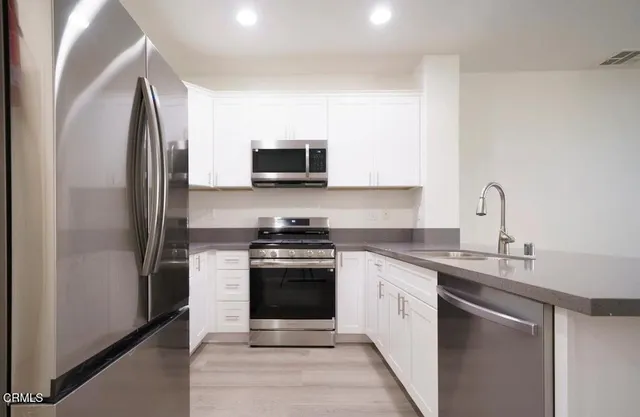 a kitchen with stainless steel appliances granite countertop a refrigerator sink and stove