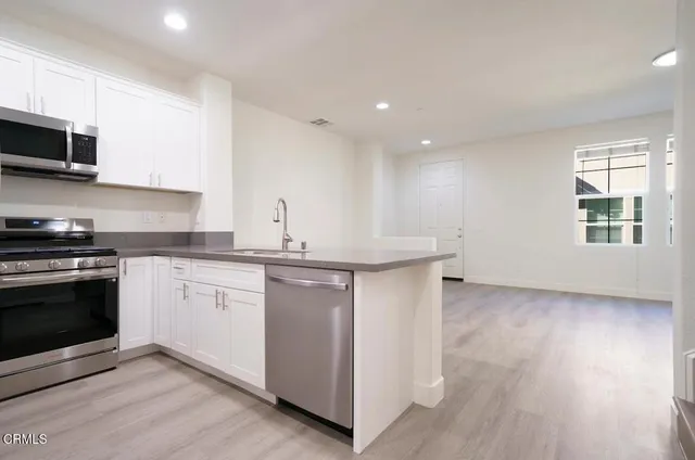 a kitchen with stainless steel appliances granite countertop a sink a stove a microwave and cabinets