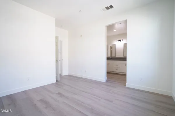 a view of an empty room with wooden floor and a bathroom