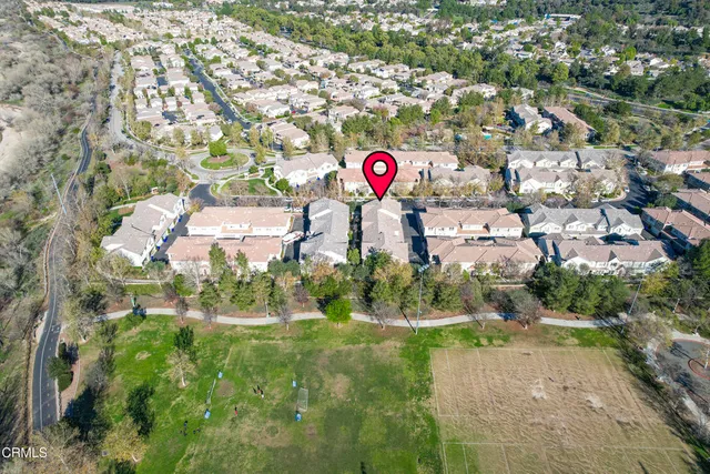 an aerial view of residential houses with outdoor space and trees
