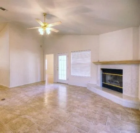 a view of an empty room with chandelier fan and fire place