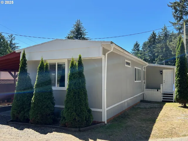 a view of a white house next to a yard