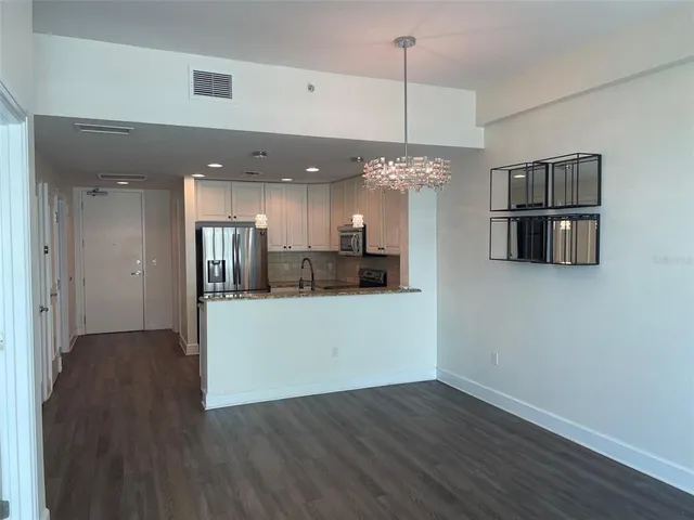 a view of a kitchen with a refrigerator a ceiling fan and wooden floor