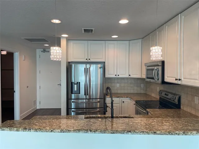 a kitchen with kitchen island granite countertop a refrigerator and a sink