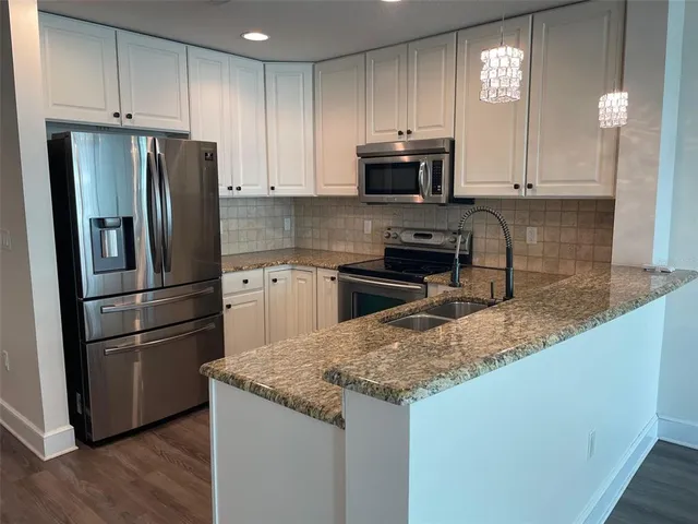 a kitchen with granite countertop a refrigerator stove and microwave