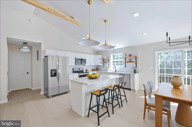 a open kitchen with stainless steel appliances granite countertop a sink a stove a refrigerator and white cabinets with wooden floor