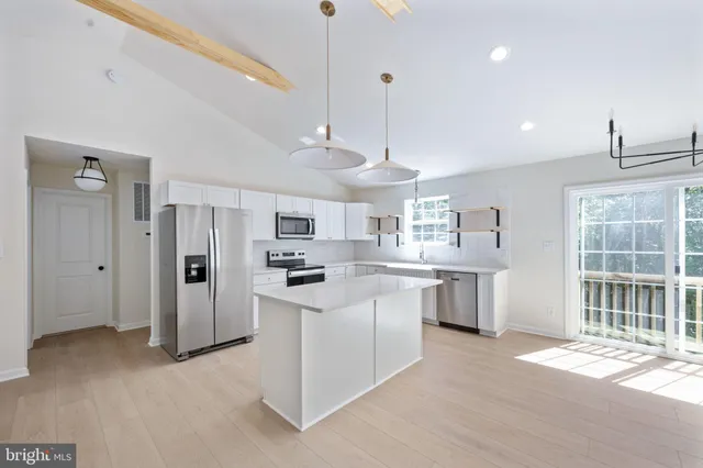 a kitchen with stainless steel appliances a sink a stove a refrigerator cabinets and chairs