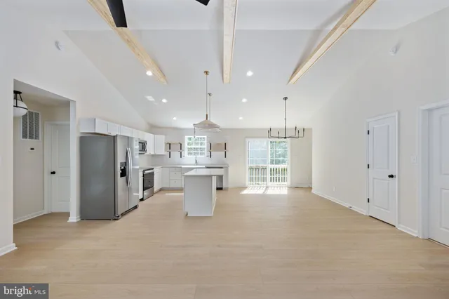 a kitchen with stainless steel appliances granite countertop a sink a stove a refrigerator and island with wooden floor