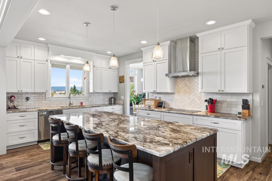 1726 Little Bear Ridge Road Troy, ID 83871 - Photo 16 of 50 Expansive kitchen island with a stone countertop, white shaker cabinetry with soft-close drawers, stainless steel GE appliances, herringbone tile backsplash, and LVP flooring
