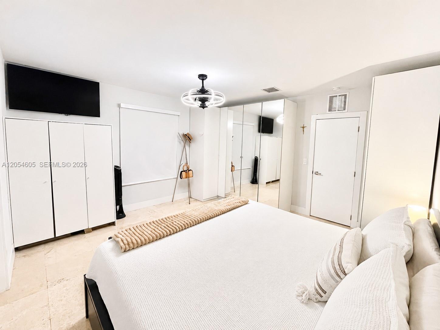 3538 Southwest 1st Avenue, Unit 1 Miami, FL 33145 - Photo 3 of 20 Spacious master bedroom featuring a walk-in closet, additional French-style closets, and a private master bathroom. The room offers generous storage, a bright neutral design, mirrored closet doors, and ample space for a large bed and furnishings, creating a comfortable and functional primary suite.