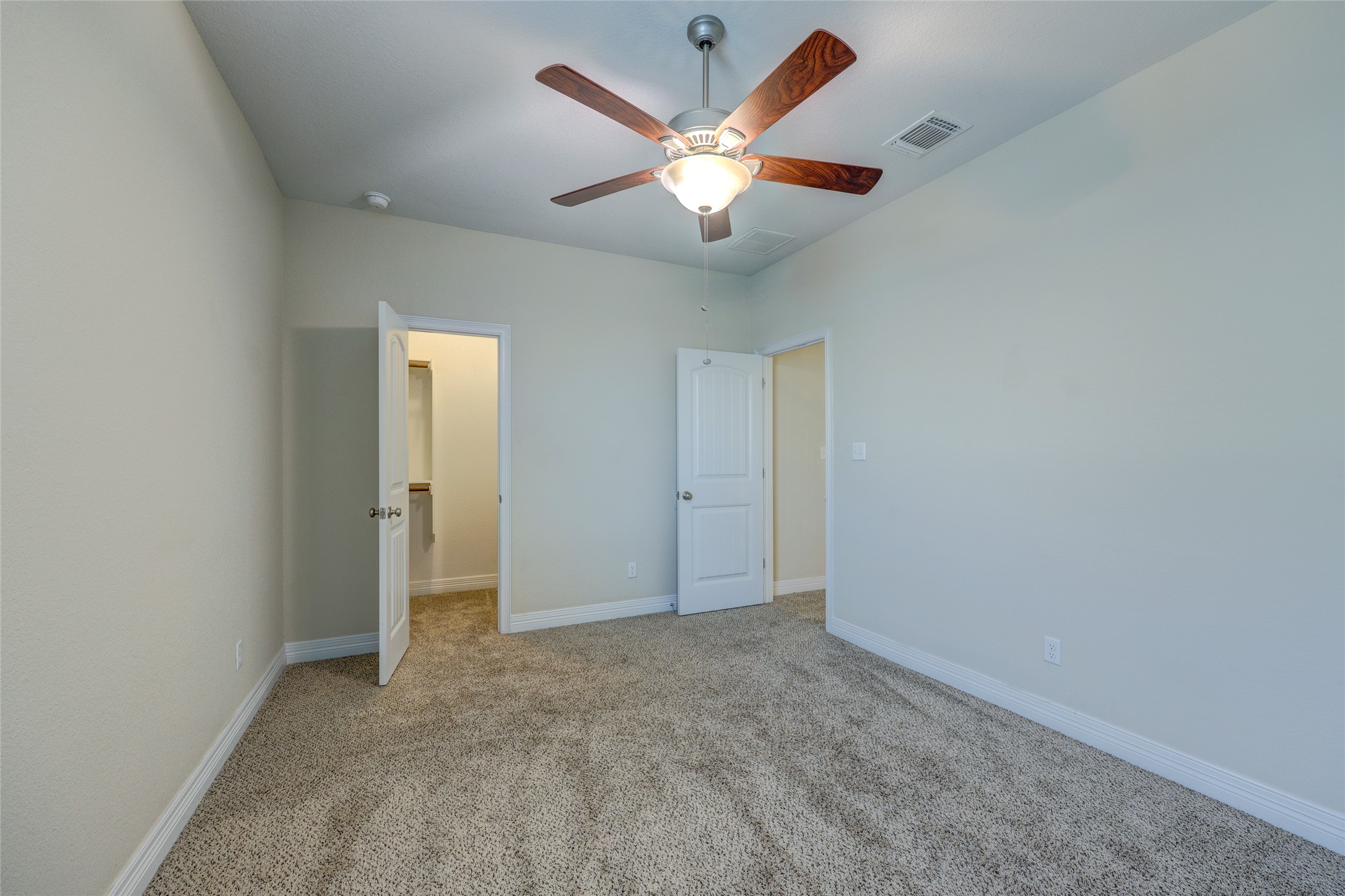 409 Betony Loop Buda, TX 78610 - Photo 23 of 38 A comfortable bedroom with plush carpeting and a modern ceiling fan, offering a serene retreat.