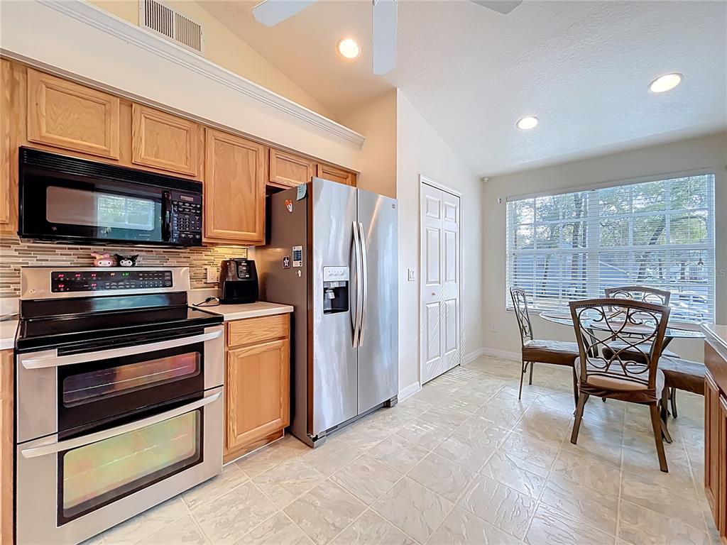 1050 Loch Vail, Unit 21 Apopka, FL 32712 - Photo 17 of 46 a kitchen with stainless steel appliances granite countertop a stove a refrigerator microwave a sink dishwasher and wooden cabinets
