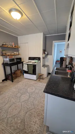 a kitchen with stainless steel appliances a stove a sink cabinets and a living room