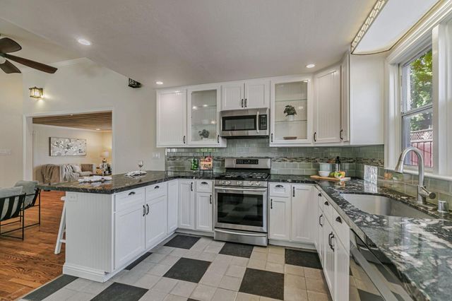 a kitchen with granite countertop a stove top oven sink and cabinets
