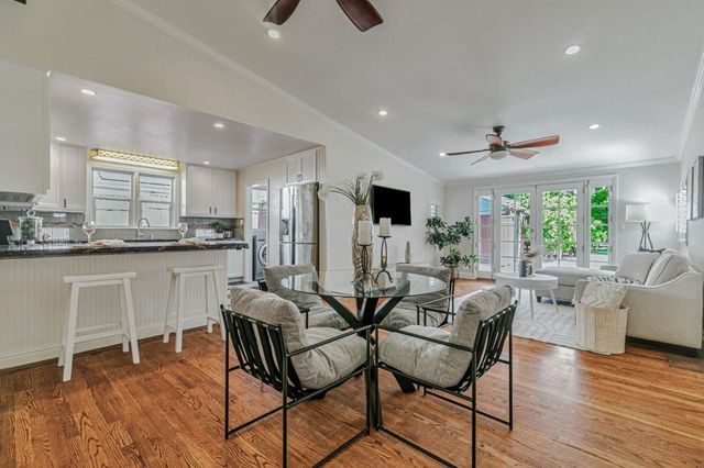 a kitchen with stainless steel appliances kitchen island granite countertop a dining table chairs and white cabinets