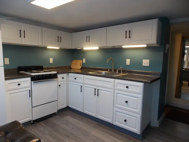 a kitchen with granite countertop white cabinets and white appliances