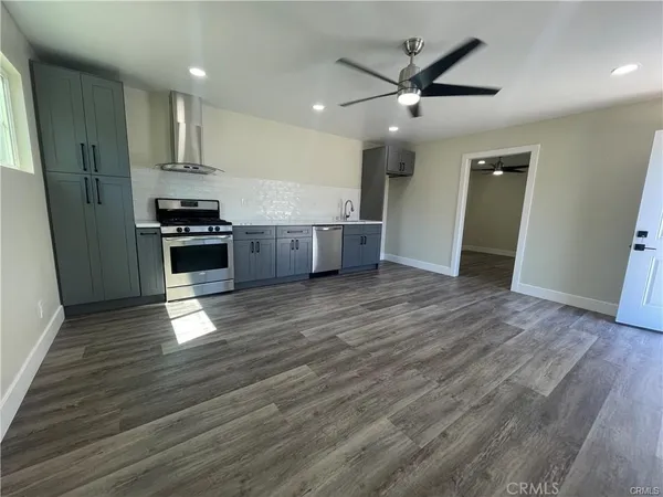 a kitchen with stainless steel appliances granite countertop a refrigerator a sink and wooden floors