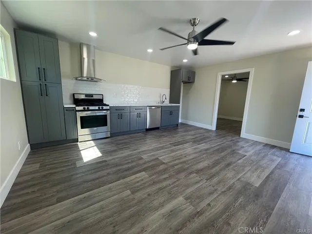 a kitchen with stainless steel appliances granite countertop a refrigerator a sink and wooden floors