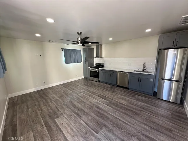 a large kitchen with stainless steel appliances a large counter top and wooden floor
