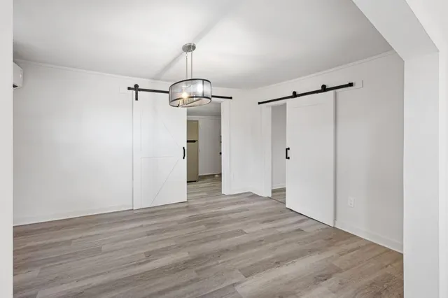 a view of a hallway with wooden floor and a refrigerator