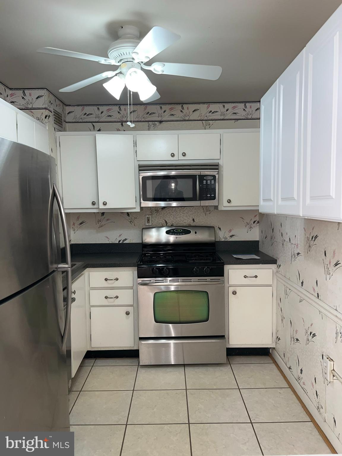 130 Slade Avenue, Unit 406 Baltimore, MD 21208 - Photo 7 of 11 a kitchen with a stove a sink and a refrigerator