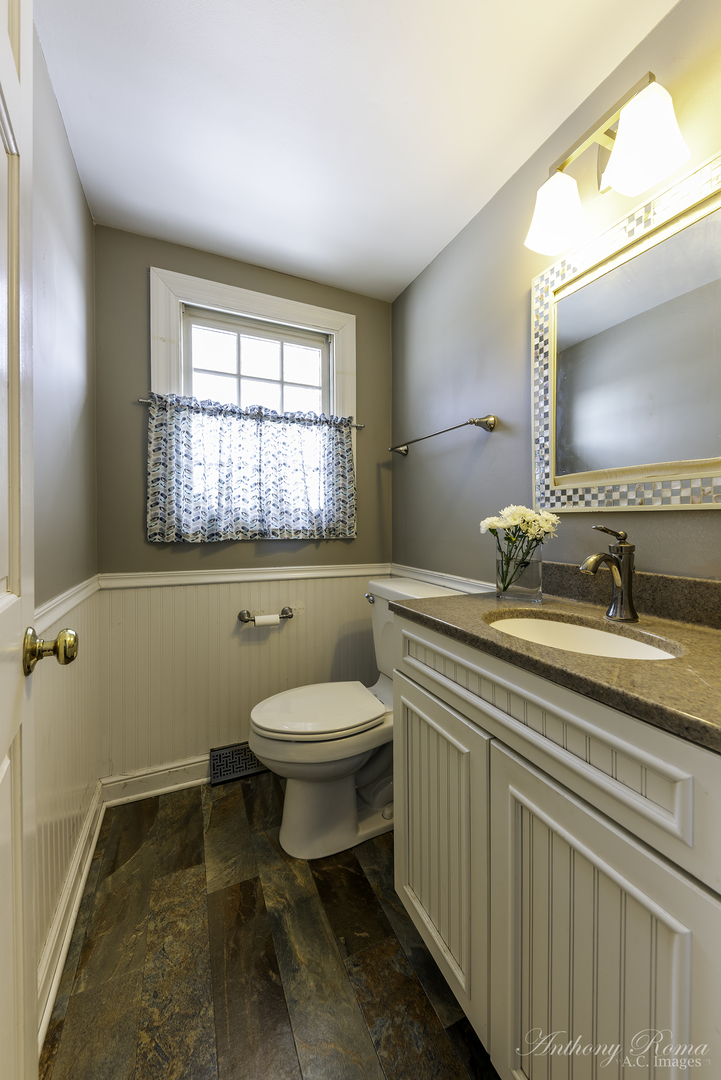 533 Beck Road Lindenhurst, IL 60046 - Photo 11 of 19 a bathroom with a toilet sink a mirror and a window