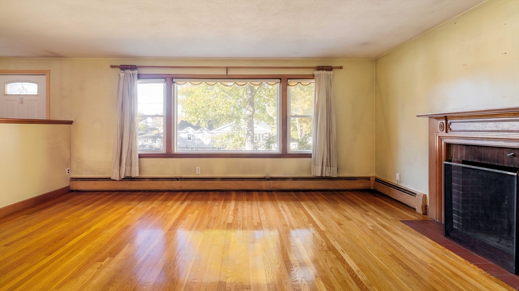 97 MacArthur Road Stoneham, MA 02180 - Photo 4 of 30 a view of an empty room with wooden floor and a window