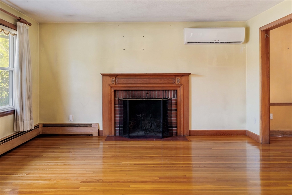 97 MacArthur Road Stoneham, MA 02180 - Photo 7 of 30 a view of an empty room with wooden floor and a fireplace
