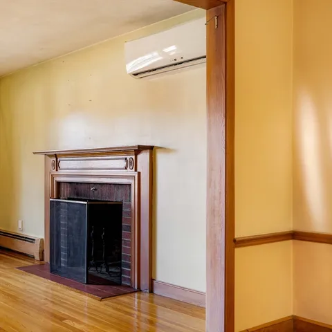 a view of an empty room with wooden floor and a fireplace