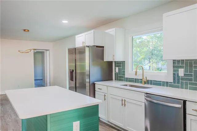 a kitchen with stainless steel appliances a sink cabinets and a window