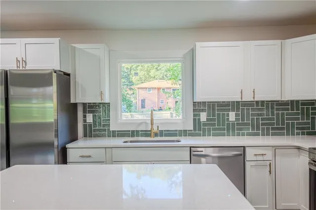 a kitchen with kitchen island a counter top space a sink stainless steel appliances and cabinets