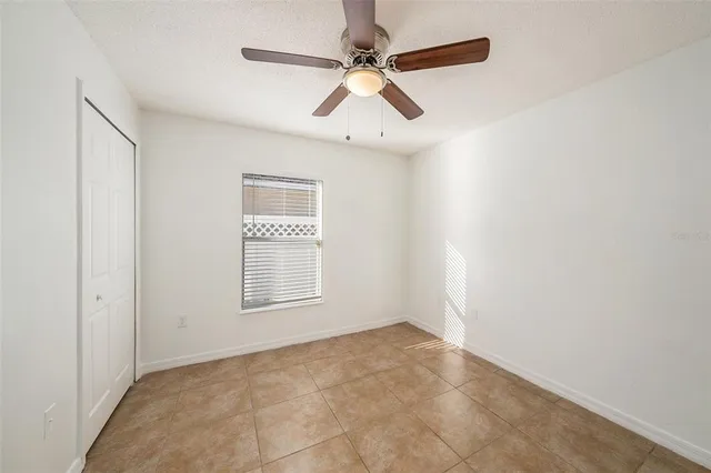 an empty room with windows and fan