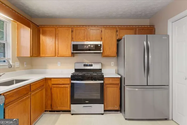 a kitchen with stainless steel appliances granite countertop a refrigerator a stove a sink and a window