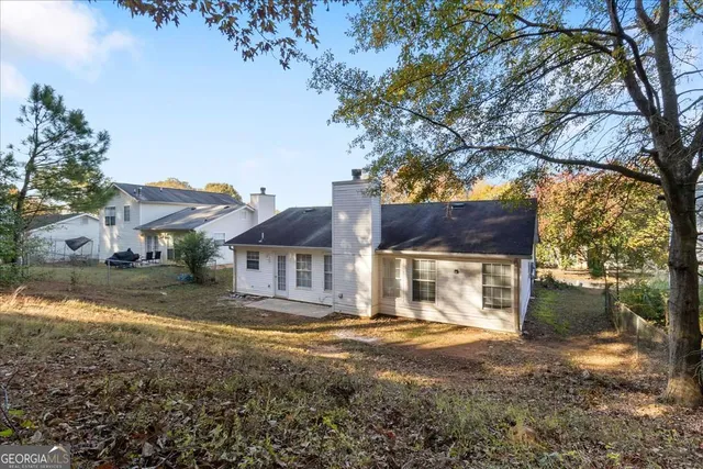 a front view of a house with a yard and large trees