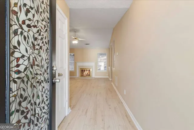 a view of a hallway with wooden floor and a bathroom