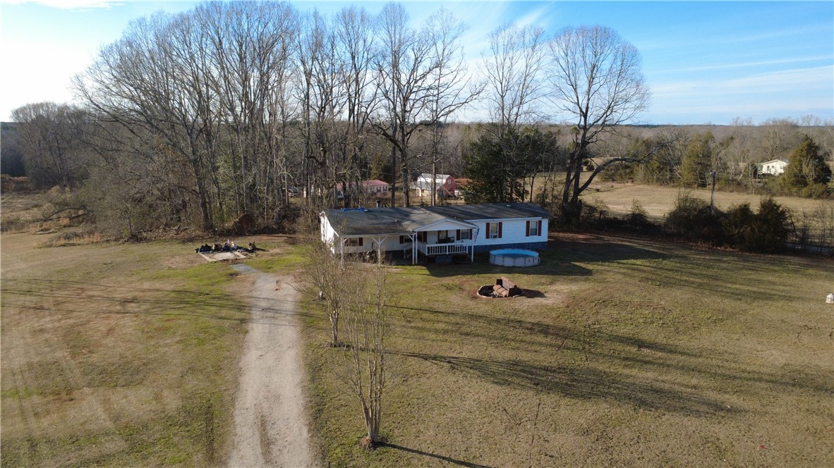 145 Finley Road Belton, SC 29627 - Photo 6 of 9 This expansive rural property features a welcoming front porch and mature trees under a clear sky.