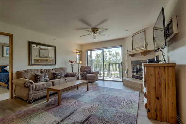 a living room with furniture a ceiling fan a fireplace and a large window