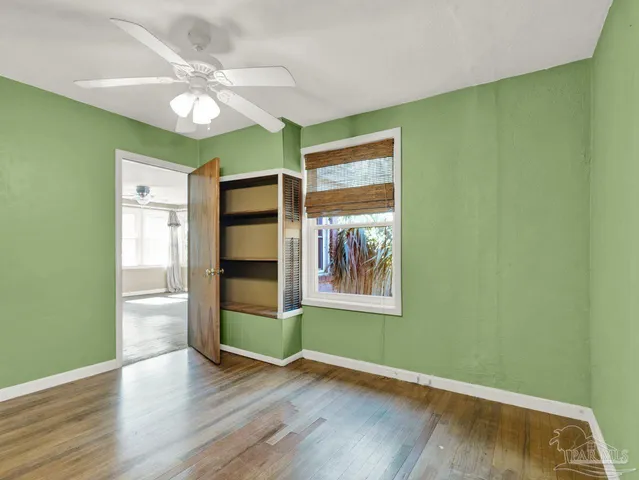 a view of an empty room with a window and wooden floor