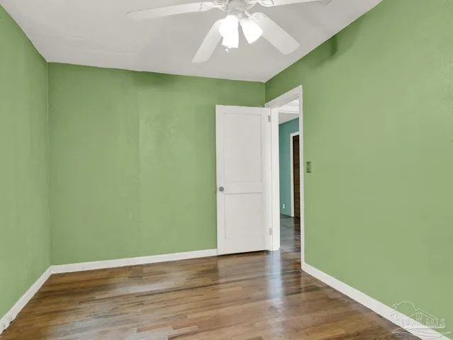 a view of empty room with wooden floor and fan