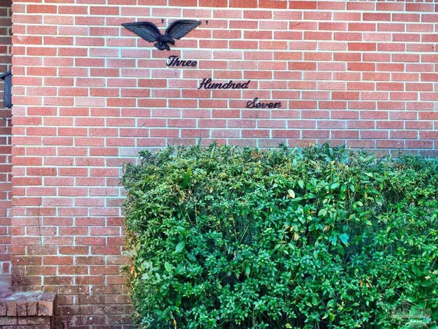 a view of a brick wall with plants in front of door