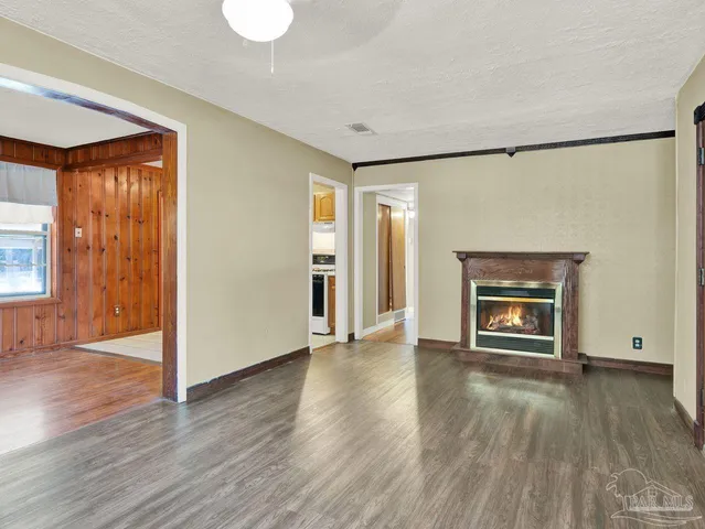an empty room with wooden floor fireplace and windows