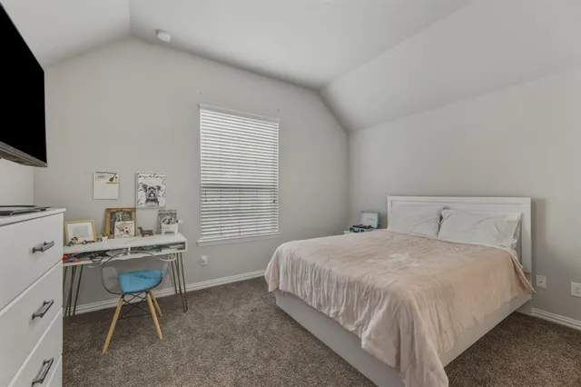 a bedroom with a bed a chair and a flat screen tv