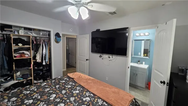 a bedroom with a bed and a flat tv screen on the dresser