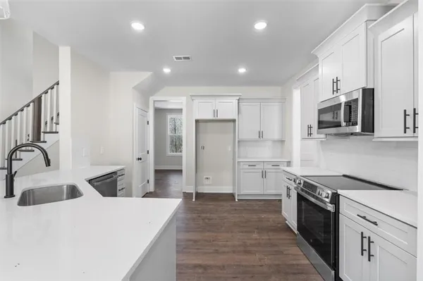 a kitchen with stainless steel appliances white cabinets and a stove a oven with wooden floor