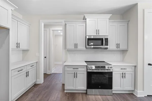 a kitchen with stainless steel appliances kitchen island granite countertop a sink a refrigerator and a wooden floor