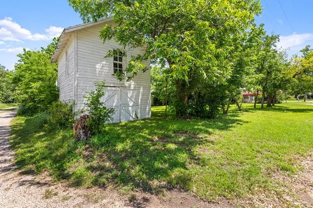 a backyard of a house with plants and large trees
