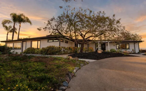 a front view of a house with a garden and tree