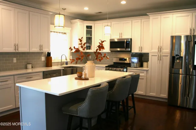 a kitchen with stainless steel appliances granite countertop a sink a stove a refrigerator a microwave oven with a dining table and chairs